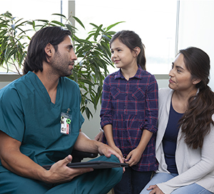 Un proveedor de atención médica habla con una mujer y una niña.